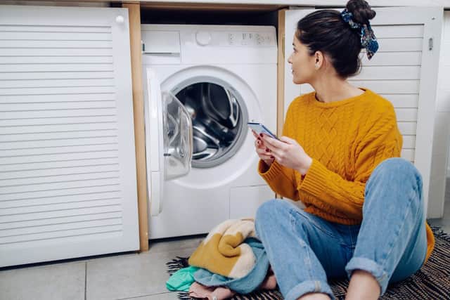 Young woman using online tutorial for learning how to adjust her washing machine.