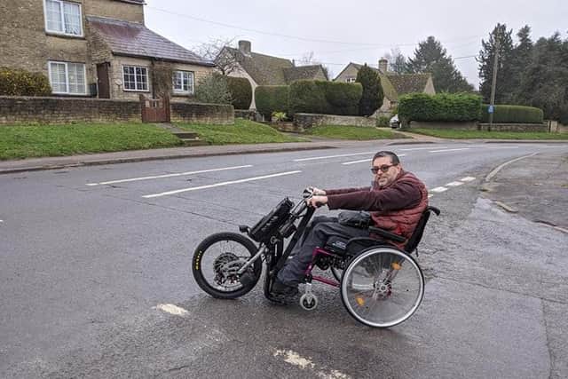 Richard Brown, leader of the Safe Roads in Middle Barton campaign, tries to cross the B4030, uphill from the school, in his disability scooter