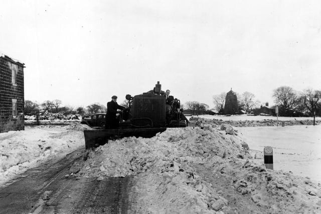 A snow plough at work on Coal Road. The old windmill on Mill Green can be seen in the background.
