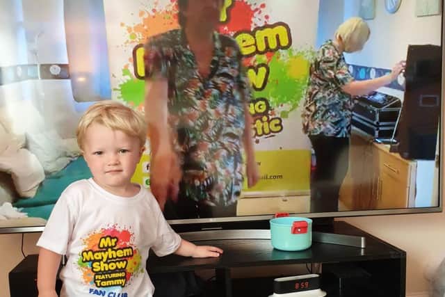 Two-year-old Joshua Coombes wearing his Mr Mayhem Show T-shirt as one of the episodes plays on TV
