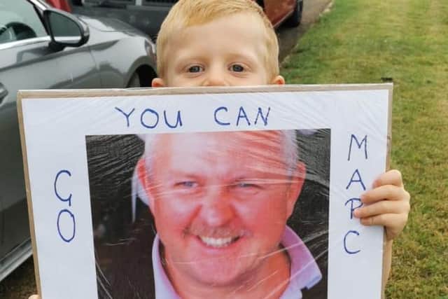 Marc's son, Jake, holds a photo poster of Simon, Marcs father in law.