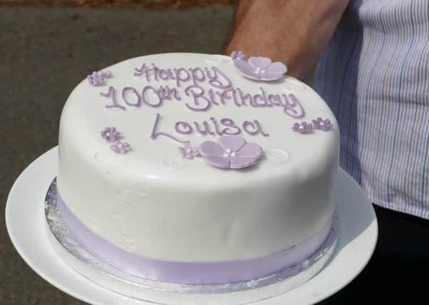 A lavender coloured fruit cake held by Alan Hill, Louisa's son (photo by David Beaumont)