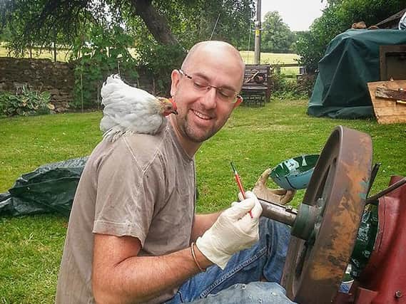 Nathan Portlock-Allan working on one of his restoration projects with encouragement from a hen