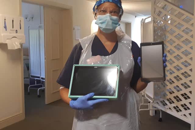 A nurse at Katharine House Hospice holding tablets used to interact with families of patients