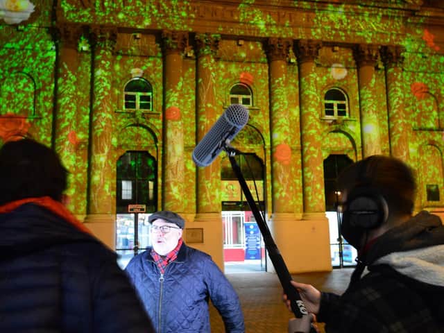 Cllr Kieron Mallon faces the camera as the winter lights film lights up the Castle Quay entrance in Cornhill.