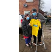 Julie Hyde stands next to Ben Cox, as he holds the autographed Banbury United Football Club jersey which has boosted his spirits while he battles long Covid