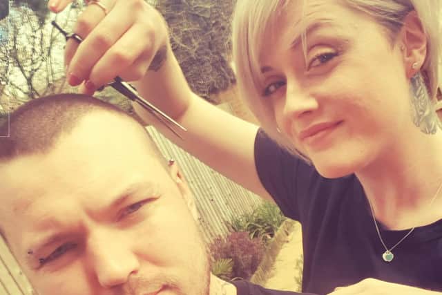 Amanda-Gayle Ostler tidies up her husband Jake's hair after manicuring the lawn for her social media video