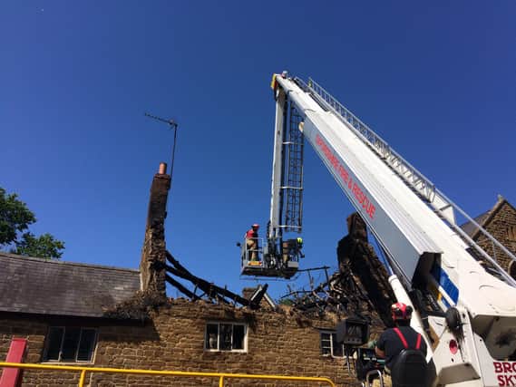 Firefighters are lowered into the roof space of the cottage in Hornton to check heat readings