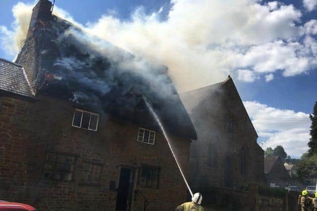 Firefighters work on putting out the fire at the thatch cottage in Hornton village