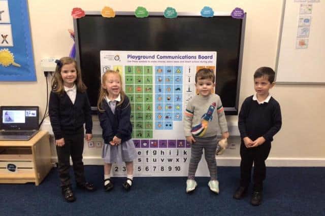 Ellie, left, and Albie (second from right) are pictured at the presentation of a speech board to Woodford Halse Primary School