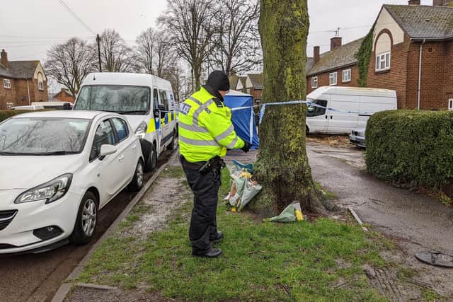 A Thames Valley Police officer looks on at the bunches of flowers in tribute left outside the Howard Road home in Grimsbury, Banbury where a man was found fatally stabbed Sunday February 13 (photo by Roseanne Edwards)