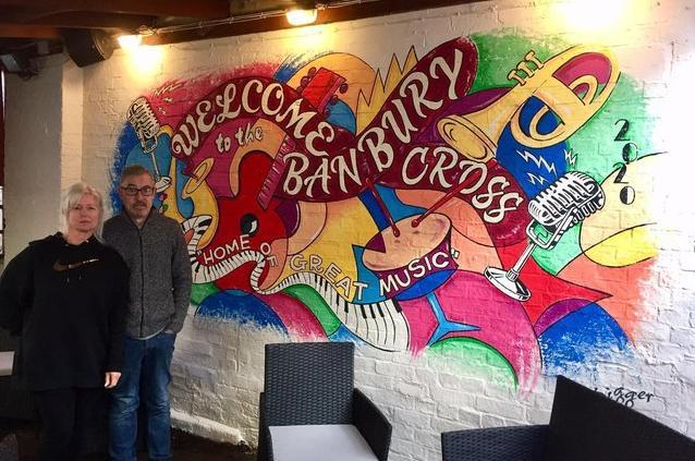 Gail and Dave Gilkes, who run the Banbury Cross pub in Butche'rs Row of the town centre, stand next to a large mural in the pub's garden done by local artist, Steve 'Digger' Gardner