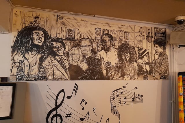 Mural of famous musicians from so and so and the publicans of the Banbury Cross pub in Butcher's Row of the town centre. Mural by Steve 'Digger' Gardner.