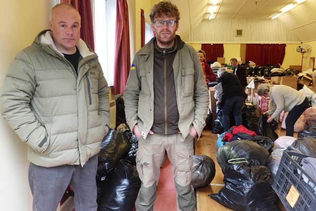 Brothers, Ian and Andrew Bathe, stand in front of the donated goods and supplies at the Chacombe Village Hall (photo by Rosy Burke)