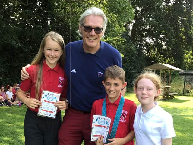 Olympic rowing gold medallist Tim Foster MBE pupils Daisy, Samuel and Evie at Deddington CE Primary School end of year outdoor celebration assembly