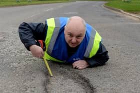 Mr Pothole, Mark Morrell, showing how deep and dangerous potholes can be in roads that have been neglected because of funding cuts