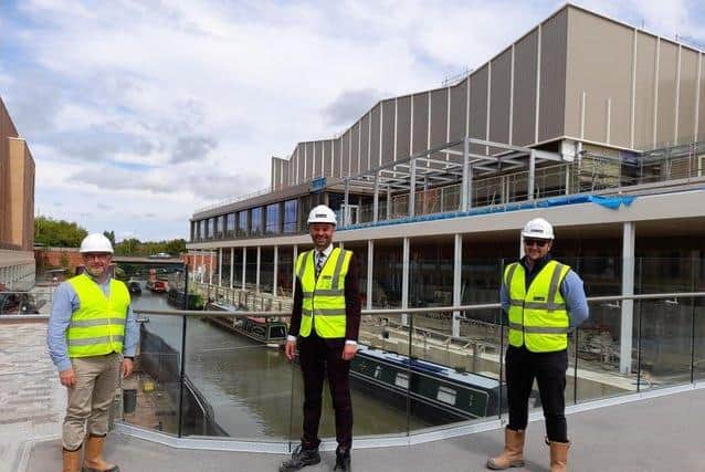 Chris Hipkiss of Cherwell District Council, Oliver Wren, Castle Quay Shopping Centre director, and Ben Parker of McLaren Construction Company pose for a photo in front of the new Castle Quay Waterfront development during construction