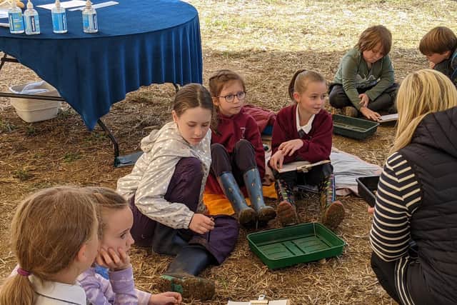 Pupils try out their own examination and description of tesserae, or mosaics, from the Roman villa site with one of Time Team's small finds experts, Danni Wootton