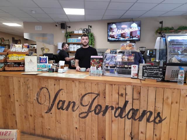 Head barista Aidan Booth holds a coffee behind the counter at VanJordans Coffee House and café.