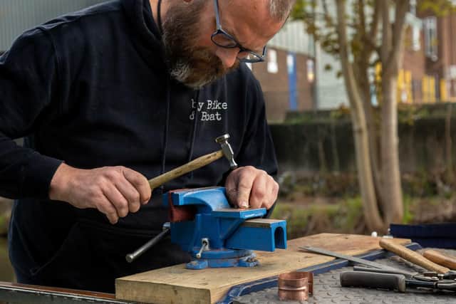 Rich McKenzie at work - his upcycled copper jewellery is made on the stern of the narrowboat
