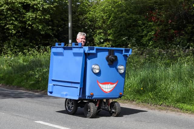 Kevin Nicks negotiates the potholes in his blue motorised wheelie bin