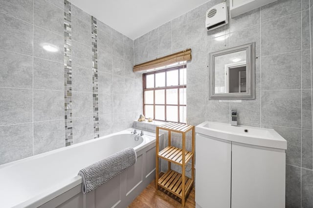 The bathroom has a modern style with tiled walls and a large bathtub.
