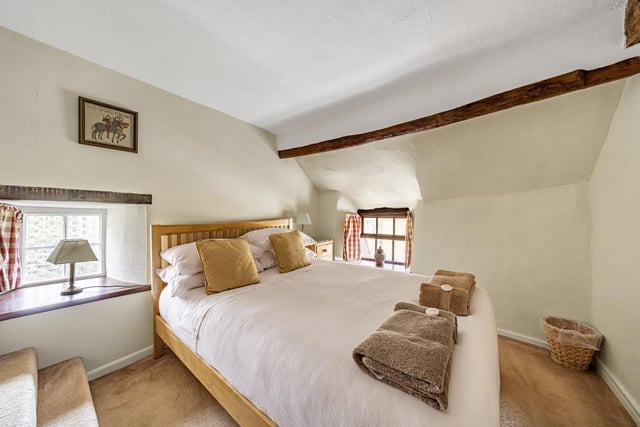 The master bedroom features exposed beams and cute small cottages windows giving the room a historic feel.
