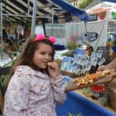 Jasmine Gilbert tastes some rum cake at the Caribbean Store with Jessica Hutchings holding the sample at the 2022 Food Festival