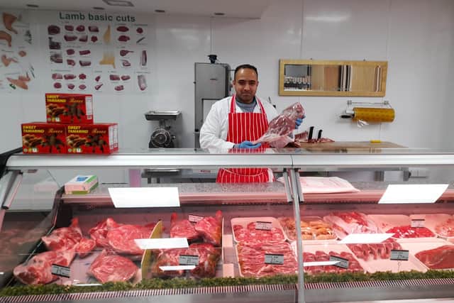 Aurangzeb Mirza, who runs the family-owned business with several relatives, holds a piece of halal meat inside the new Banbury Butchers and Supermarket