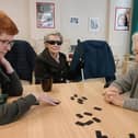 Volunteer Sarah McDonald playing dominoes with Tina and Phyllis.