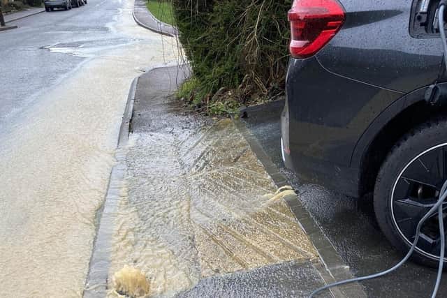 Water gushes out of the pavement and driveway of David Murray-Hundley's home in Clifton