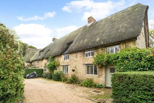 The semi-detached thatched house has a shared driveway with two other cottages.