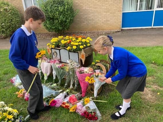 Pupils Albie and Alice place flowers with other tributes at Queensway Primary School, Banbury