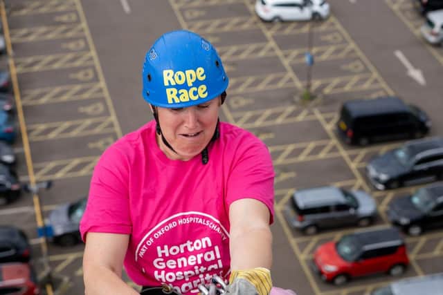Anna Brain steels herself and lowers herself down the side of the 100ft high building. Picture by Joe Baker / Oxford Hospitals Charity