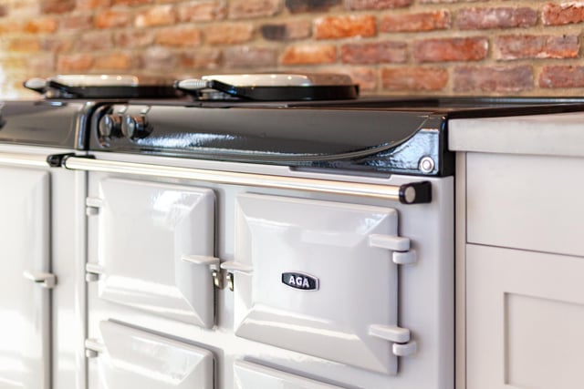 The kitchen offers a full electric four oven Aga with Induction hob between drawer units. Further storage in an open shelved larder can be found behind.