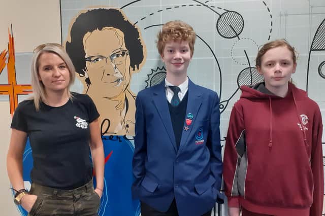 Wykham Park Academy students Geoffrey Woodward and Chloe Watts stand in front of a maths mural at the school with its artist - Lucy Barnes (photo from the school)