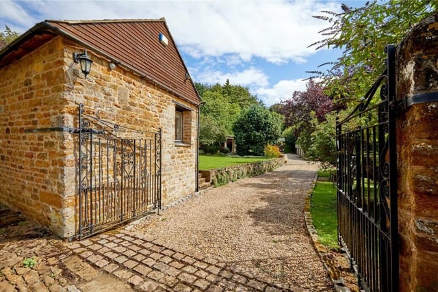 A wrought-iron gate opens to a private driveway leading to the property.