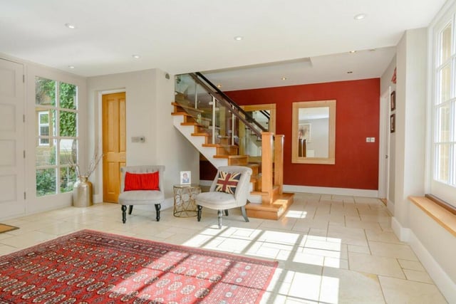 The spacious entrance hall has a coat cupboard and large double windows to the rear.