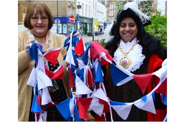 Sandra Stowe, a volunteer at the Orinoco store in High Street, handing a bundle of bunting to Banbury Cllr and Town Mayor Shaida Hussain.
