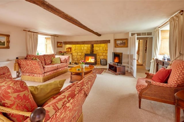 The living room has period features including exposed original beams and stone mullion windows with seats.