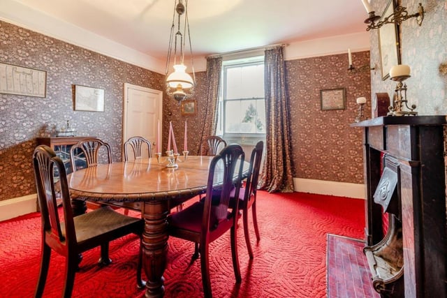 The dining room also features an open fireplace with original deep red inset tiling and an ornate marble surround.