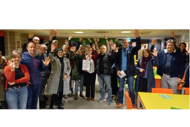 Parents raising their hands in solidarity at the previous Save Our Bus Seats meeting at The Warriner School.