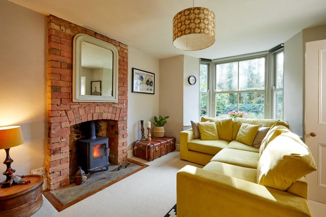 The living room has a large bay window and the original exposed brick fireplace.