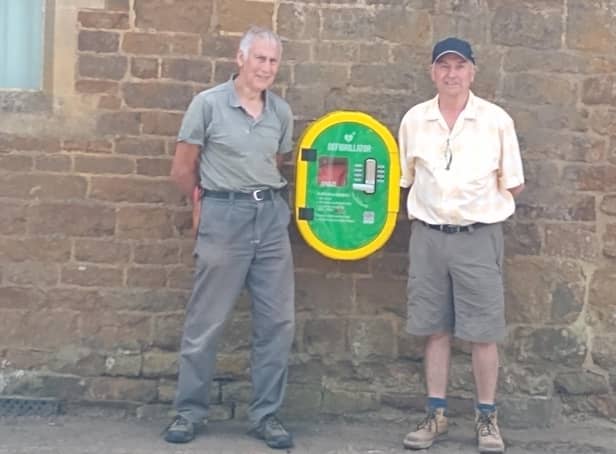 John Ellison and Nigel Davies are pictured with the defibrillator which has been fixed to the village hall wall