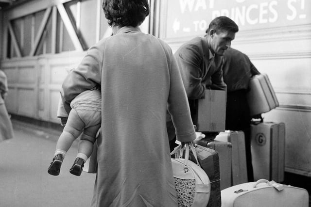 A mother carries the baby under her arm like a piece of luggage while a man gathers the suitcases together at Waverley Station in 1965.