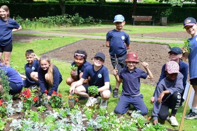 Youngsters from Harriers School get down to planting flowers in the park
