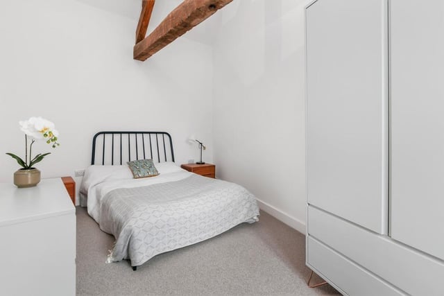 The bedroom has a high ceiling with exposed beams and a double glazed window.
