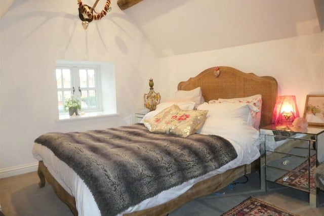 The main bedroom features window to the rear and the front, with a vaulted ceiling and exposed timber beams.