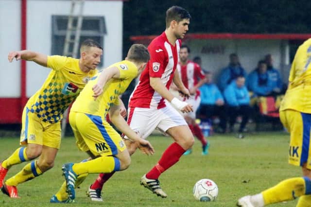 Brackley Town's James Armson leaves Stockport County's Dan Cowan and Gary Stopforth behind