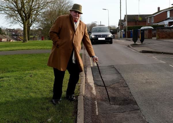 Ian Stirling showing the depth of a pothole on Queensway, Banbury NNL-180118-152056001